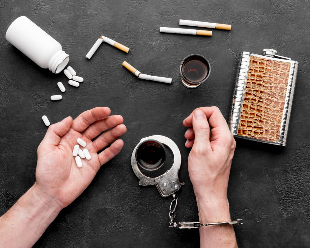 Pills, cigarettes, alcohol, and handcuffs representing substance abuse and addiction