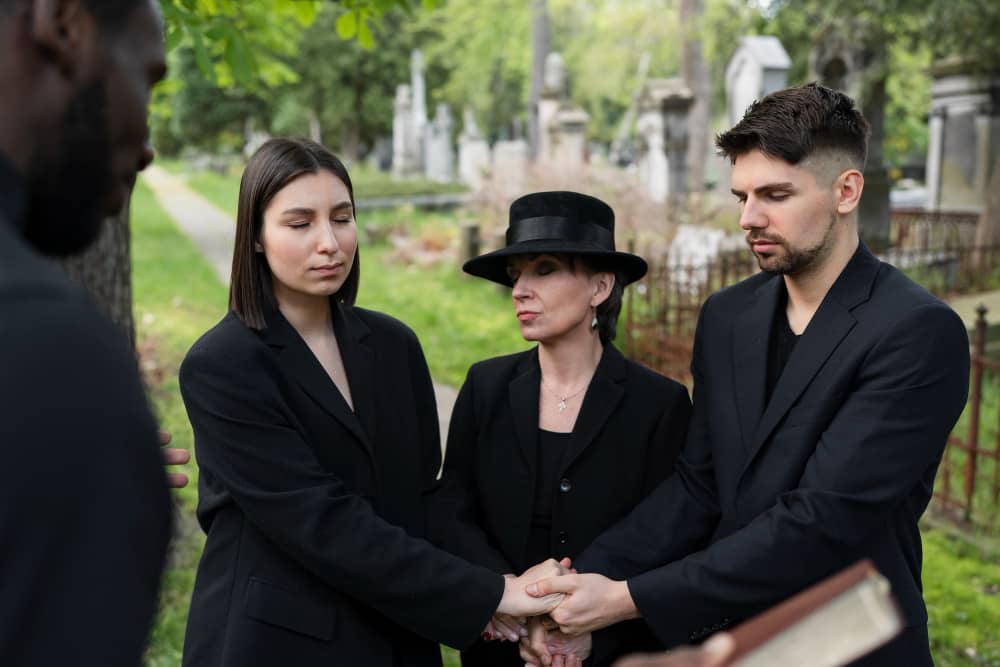 Family dressed in black mourning at a cemetery