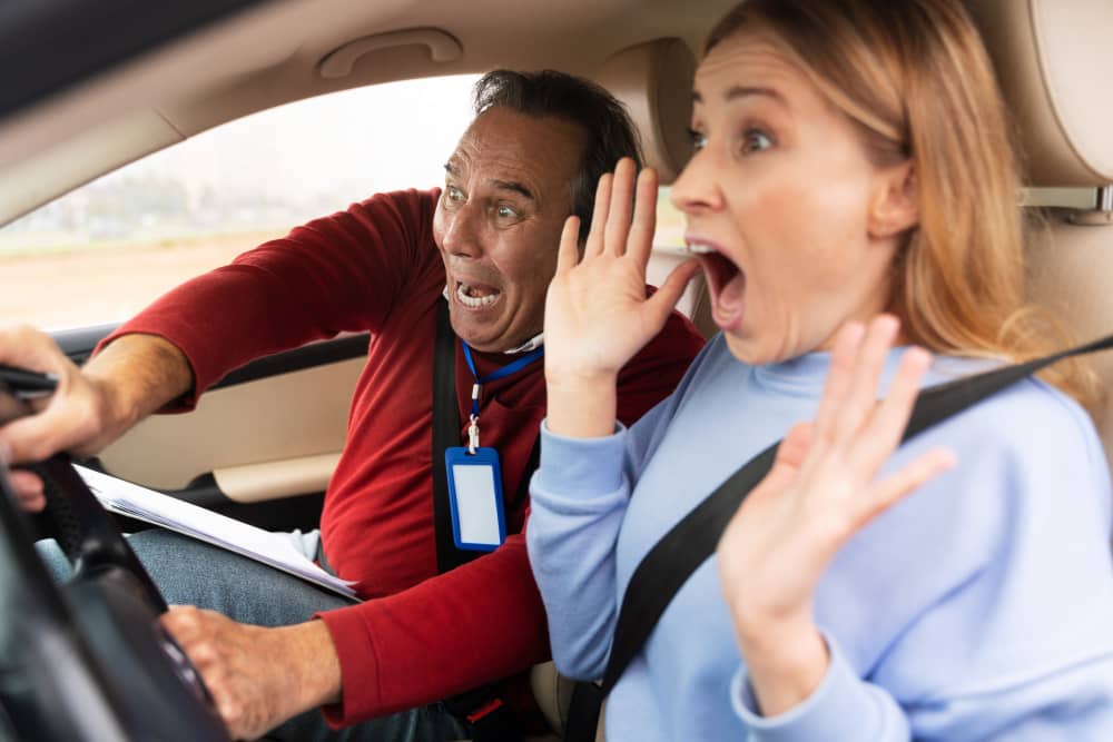Driving instructor and startled student reacting inside a car