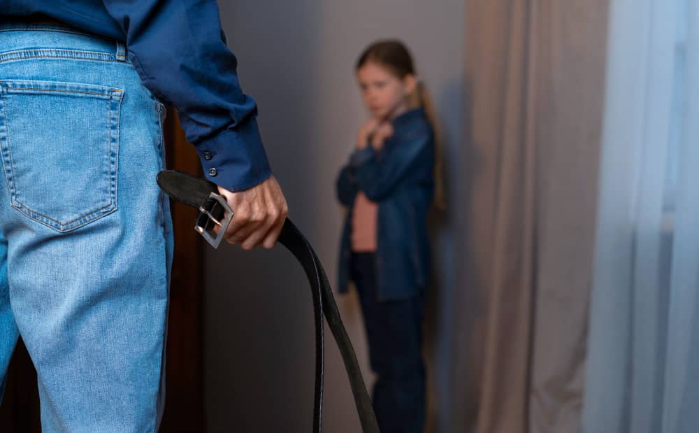 Parent holding a belt near a frightened child, representing child abuse