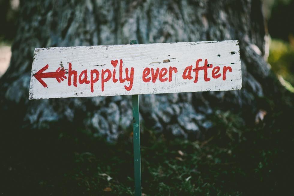 Wooden sign reading happily ever after with an arrow, nailed to a tree