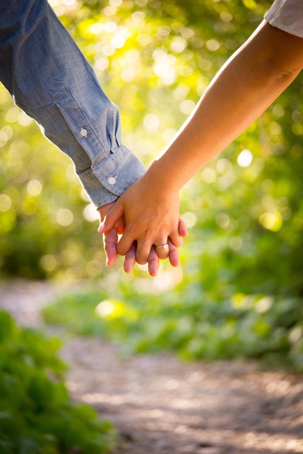 Couple holding hands while walking outdoors in the sunlight