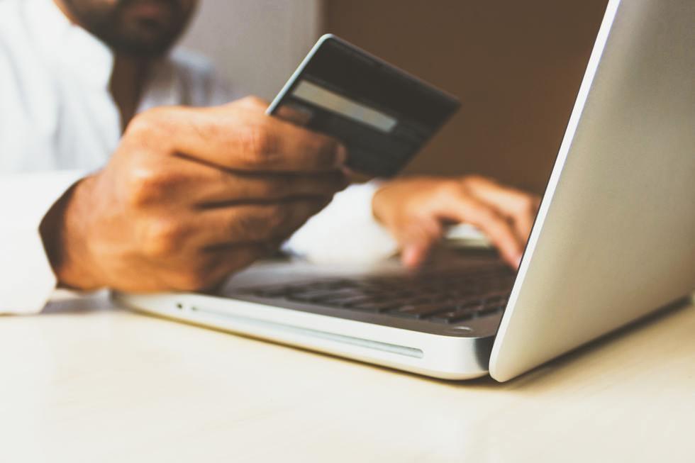 Hands typing on a laptop while holding a credit card, representing unexplained spending