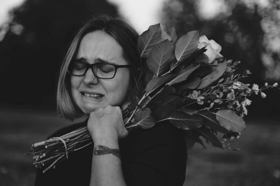 Black and white photo of a woman crying while holding flowers