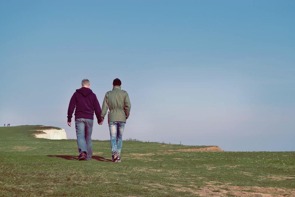 Two men walking away from the camera while holding hands